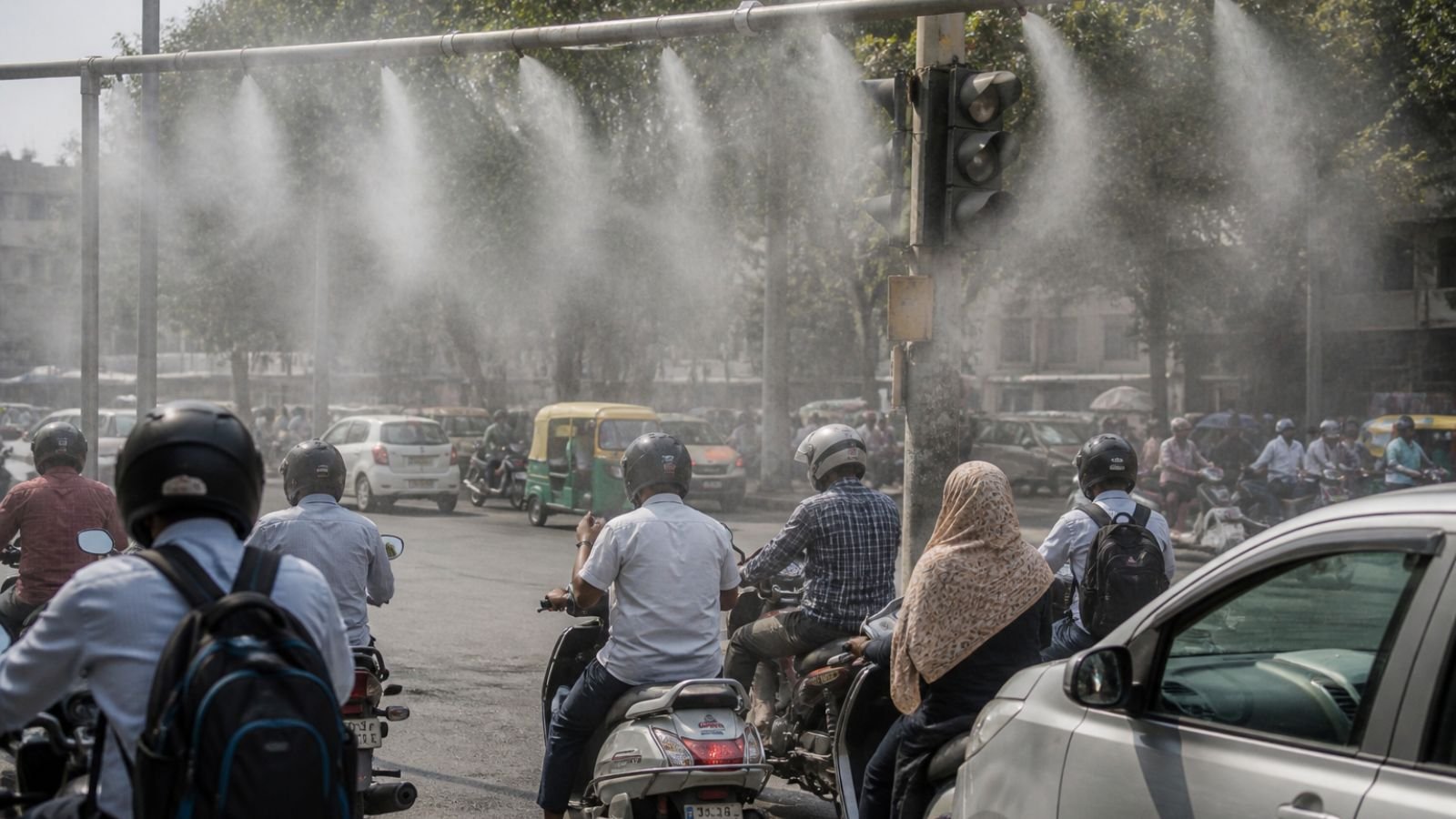 Dust suppression mist sprays over Ahmedabad traffic in heatwave conditions.